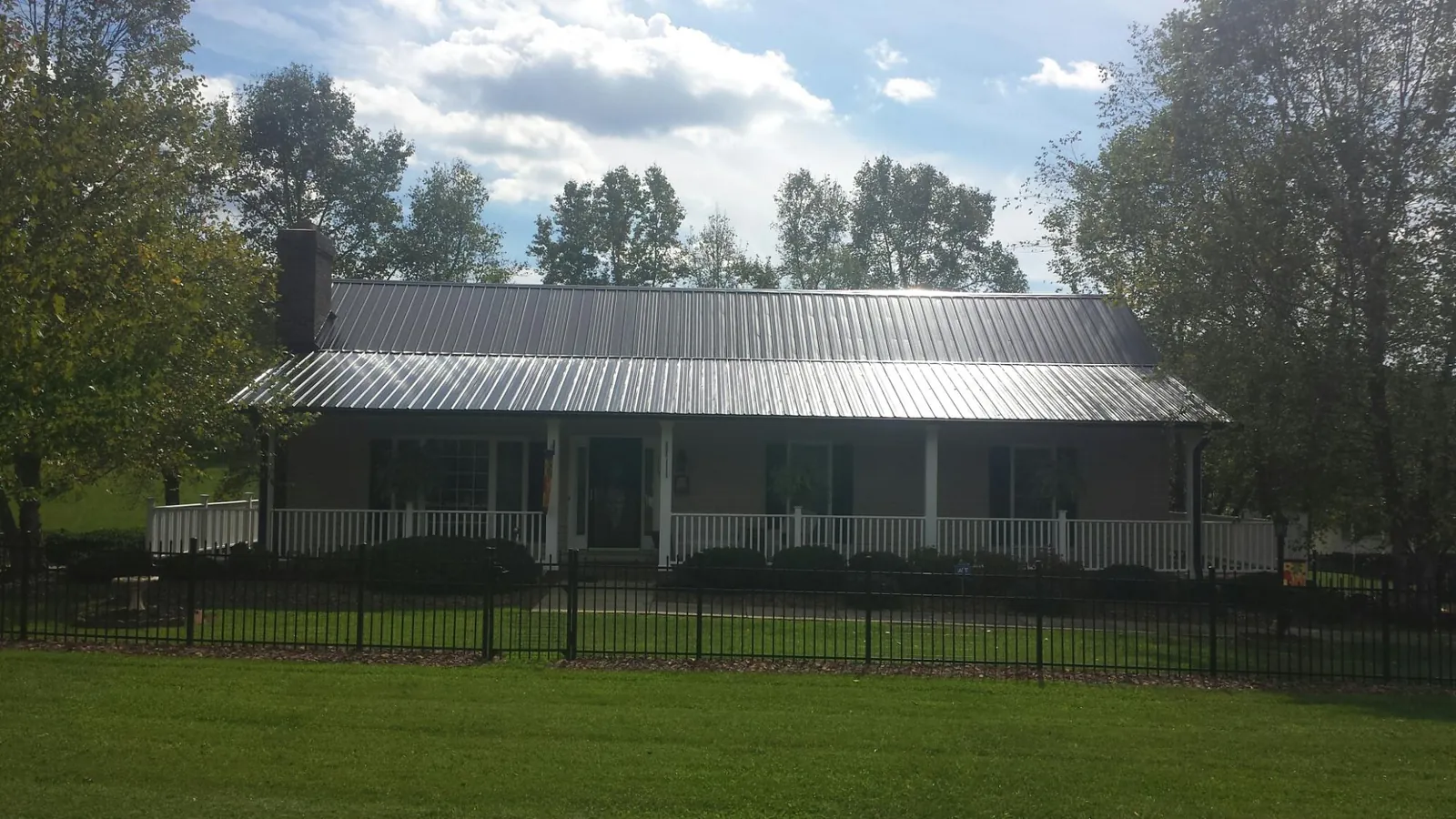 Gray metal roof on a brick ranch with a full width front porch — Gutter Guard Installation work by our crew in Carrollton