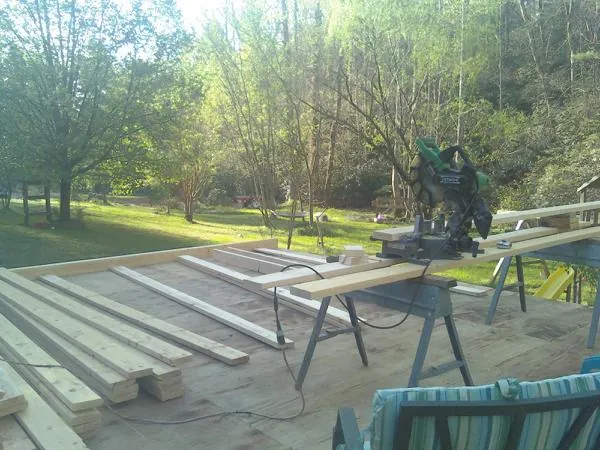 Miter saw and framing lumber on a deck under construction in Carrollton